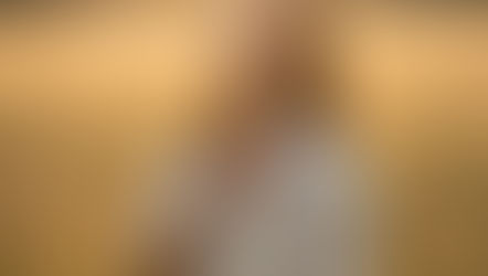 Mulher em contato com a natureza, olhos fechados e mãos sobre o coração, envolvida por luz suave dourada simbolizando reconexão e cura do feminino.