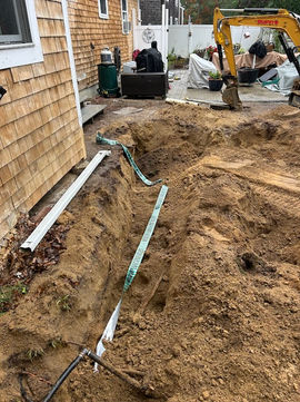 Excavator digging a trench for backyard drainage installation