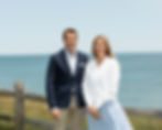 George and Mara Vasvatekis smiling with the ocean behind them.