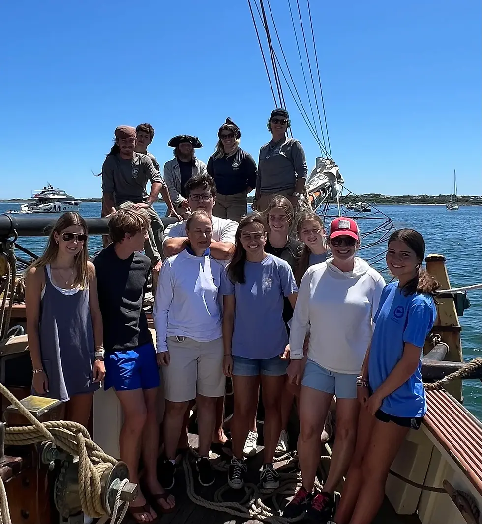 A group of kids and adults smiling for the camera on a boat