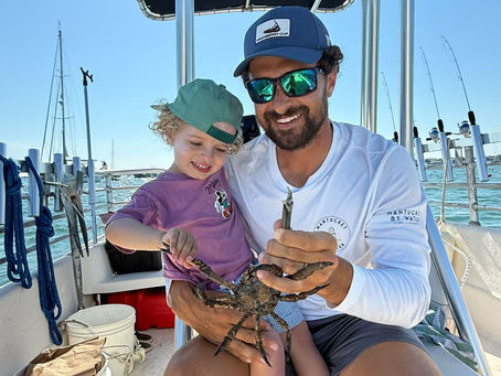 A young child and their dad on a boat holding a crab