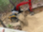 Red excavator and yellow skid steer digging a dirt trench.