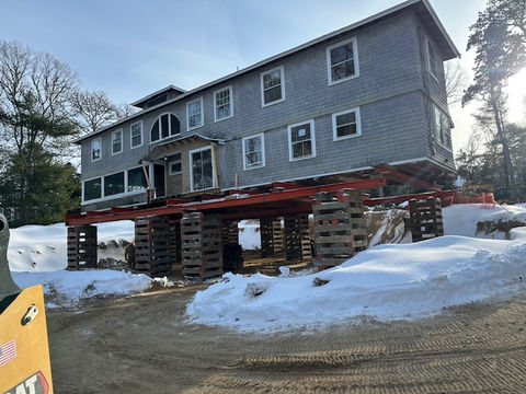 Large grey house elevated on steel beams and wood cribbing