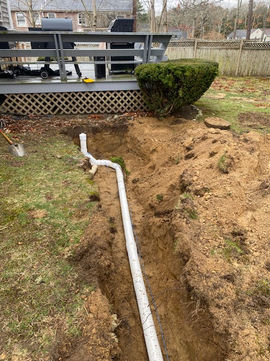 White PVC drain pipe installation in a yard trench