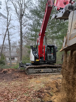 Excavator clearing land in a wooded landscape area