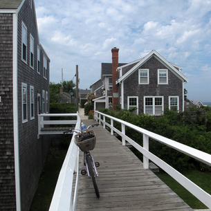 A bike leaning against the fence along a wooden dock from the ocean in Nantucket