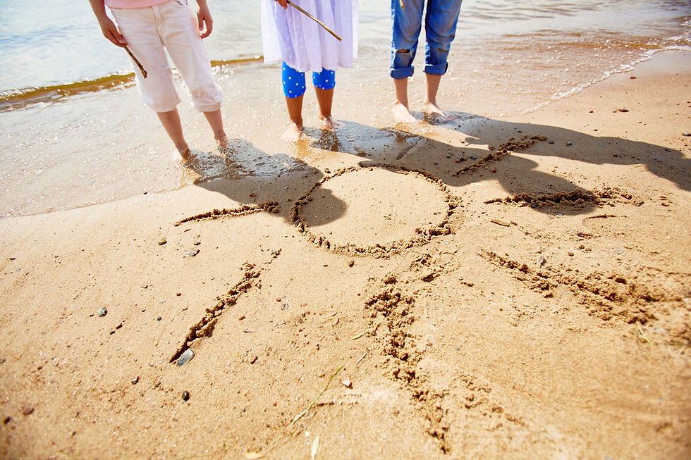 Children drawing a sun in the sand on a beach