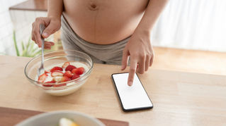 Pregnant women belly with yogurt and phone
