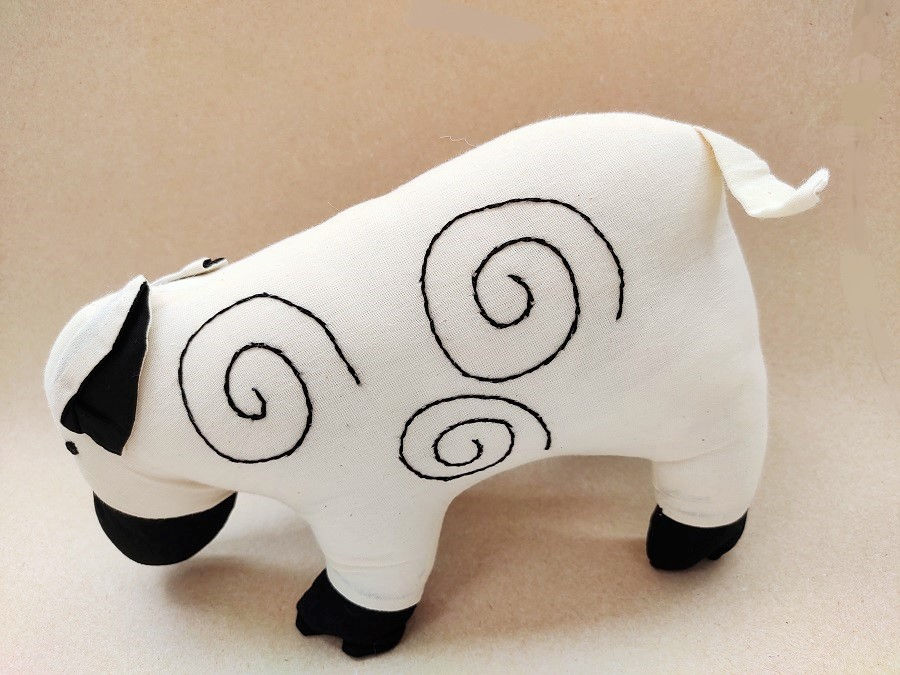 Thumbnail: Soft toy sheep made of off white cotton with a black nose and embroidered spiral pattern on the side