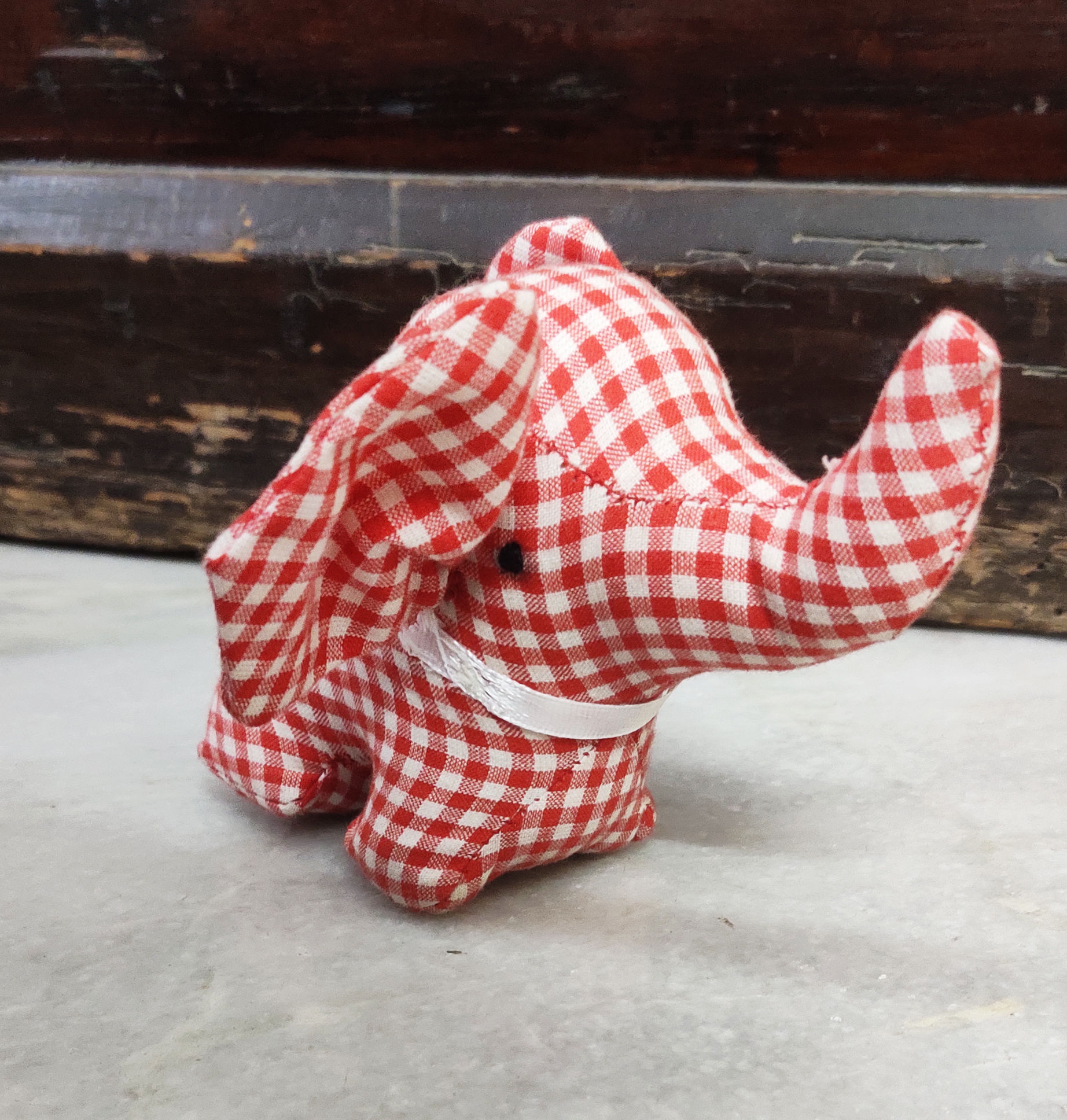 Little red and white check soft toy elephant with it's trunk lifted up