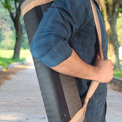 Man carrying an exercise or yoga mat over his shoulder
