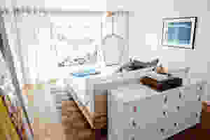 Quarto de casal com cama em ilha de frente para a janela.