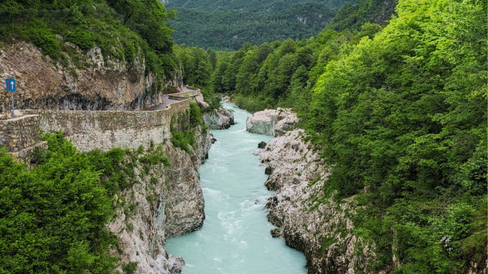 Schlucht mit der Soča in Slowenien, umgeben von steilen Felswänden und dichter Vegetation. Die kurvenreiche Straße bietet spektakuläre Ausblicke auf den Fluss.