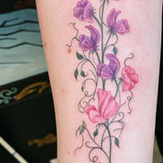 Custom botanical branch tattoo with flowers.