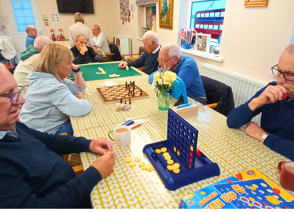 Elderly people playing board games in a communal room. Chess and Connect 4 on tables. Warm atmosphere, floral decor, and teacups present.