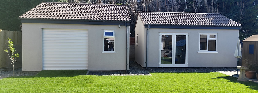 Two grey buildings with white doors and windows on a green lawn. house extension Bristol