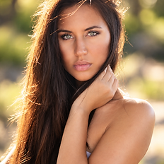 Outdoor beauty portrait of a woman with long brown hair and natural sunlight.