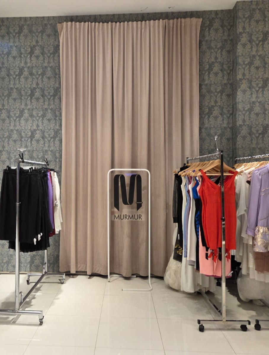Neutral-toned side display area with clothing racks – AMMS Studio retail design for MURMUR
