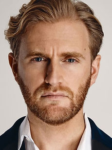 Dan D - black and white headshot of male model with swept back hair, a short beard, and wearing a denim jacket, represented by ROC Talent Agency UK