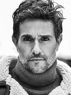 Davide - A headshot of a classic model with textured dark hair, well groomed beard, and a neutral expression, represented by Roc Talent Agency UK
