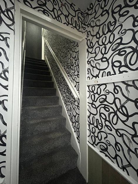 Professional wallpaper installation by JDC featuring Squiggle design across hallway and stairway, delivering a cohesive, creative, and modern interior transformation for 2026.