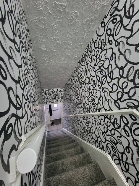 Upper hallway and staircase upgraded with Squiggle wallpaper, delivering a vibrant, continuous design that transforms a transitional area into a standout feature space.