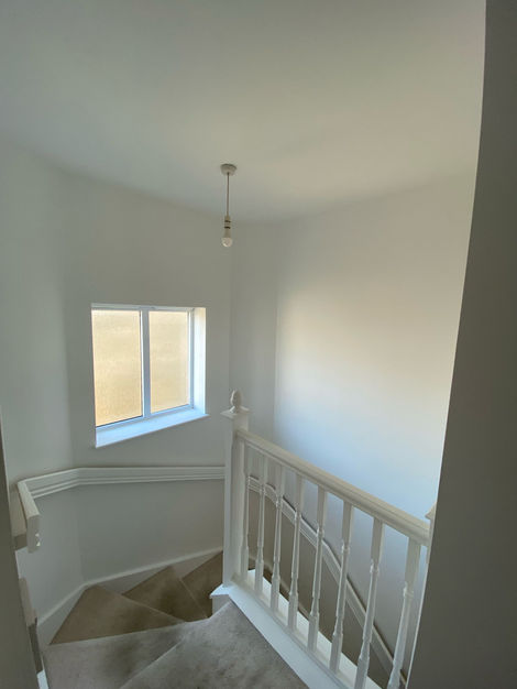 This winding staircase now shines with sharp white finishes and smooth wall coverage. A clean, modern look that elevates the entire hallway space.