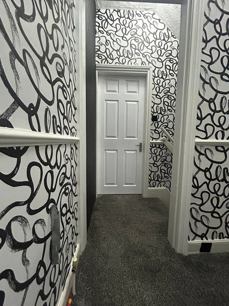 Hallway and stairway interior upgrade using Squiggle wallpaper, adding dynamic pattern movement and a modern decorative finish to a transitional home space.