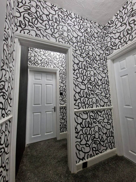 Stairway and upper hallway transformed with Squiggle wallpaper design, creating a striking visual flow and turning a transitional space into a bold contemporary interior feature.