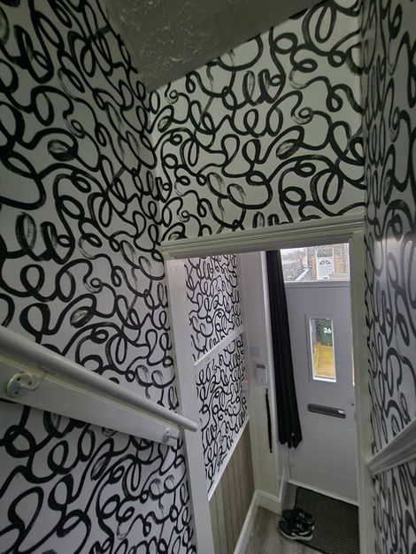 Upstairs hallway and staircase wallpaper project featuring the Squiggle graphic design, adding movement, personality, and a contemporary decorative finish across the full circulation space.