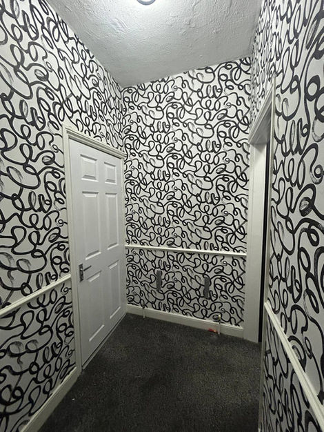 Staircase and hallway wallpaper transformation featuring Squiggle design, creating a bold contemporary statement with flowing doodle-inspired visuals and clean execution.
