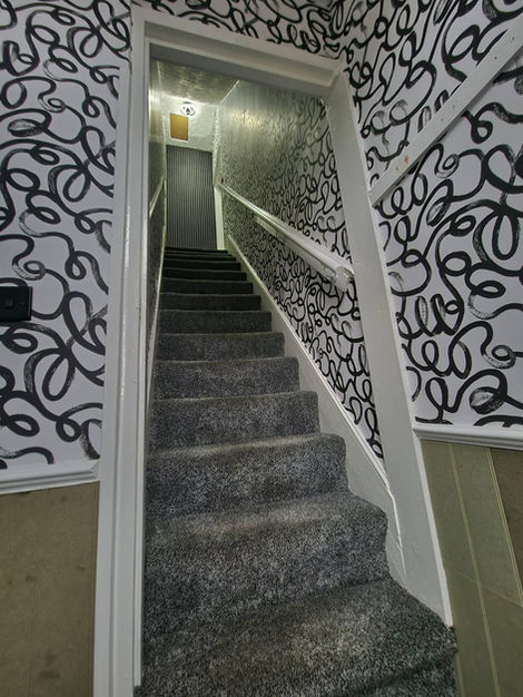 Modern wallpaper installation in hallway and stairway using Squiggle pattern, adding a dynamic, doodle-inspired aesthetic with clean execution and cohesive decorative styling.