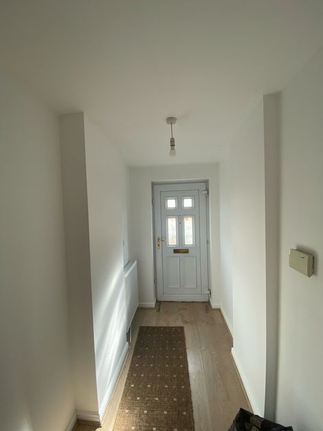 Freshly painted entrance hallway with clean white walls and natural light enhancing the space. A sleek and welcoming first impression for this property.