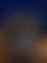 Illuminated sphere with mountain cutouts in front of a lit Inverness Castle at night. Dark blue sky, statue of Flora MacDonald on the right, and a pathway nearby.