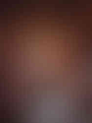 Wooden fireplace with carved figures and statues in the Red Drawing Room at Brodie Castle. Vases on mantel, dried floral arrangement in hearth. Warm, ornate setting.