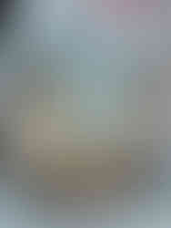 Cupcake with white frosting and a small snowman decoration, adorned with blue and white snowflake sprinkles and a silver ball.