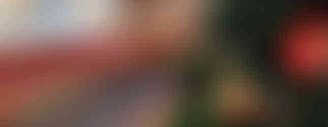 Christmas tree with red and gold ornaments in a cosy lounge. Red sofas and decorated tables with drinks in the background. Festive mood.