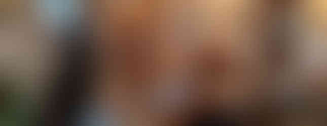 Cosy dining room with a decorated Christmas tree, wooden table set for tea, festive décor, framed photos, and a porthole window.