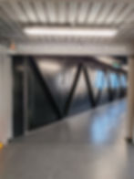 A gray corridor with a sign saying, "Thank you for visiting The Royal Yacht Britannia." Bright lights and black metal wall panels line the walkway.