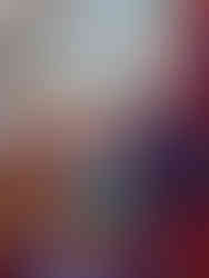 Craft display with colourful knitted items, tinsel, candles, and glassware on a wooden table. Festive lights and "No Touching" sign add warmth.