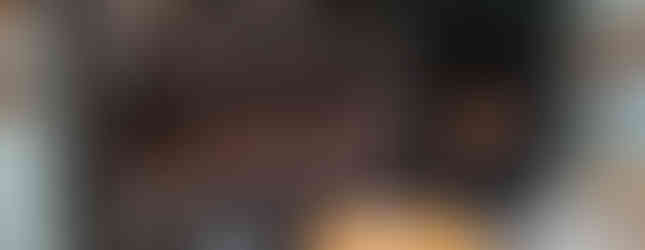 Victorian kitchen at Brodie Castle with black stoves, copper pots, and brass buckets. Light blue walls, wooden tables, and chairs create a nostalgic ambiance.