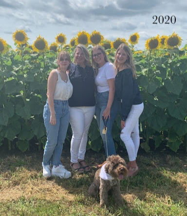 mother, three daughters and dog in sunflower field