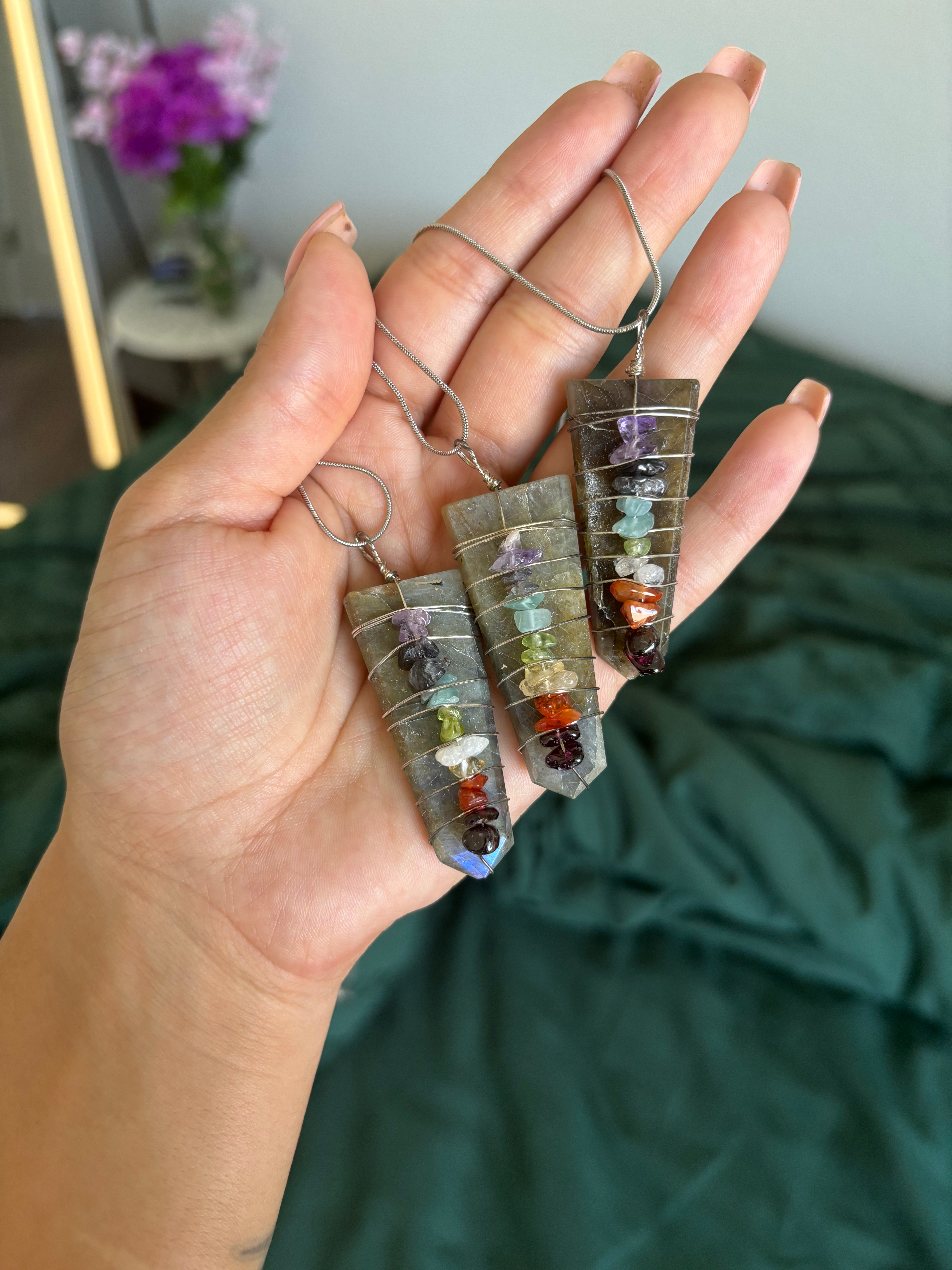 hand holding crystal chakra pendant necklaces