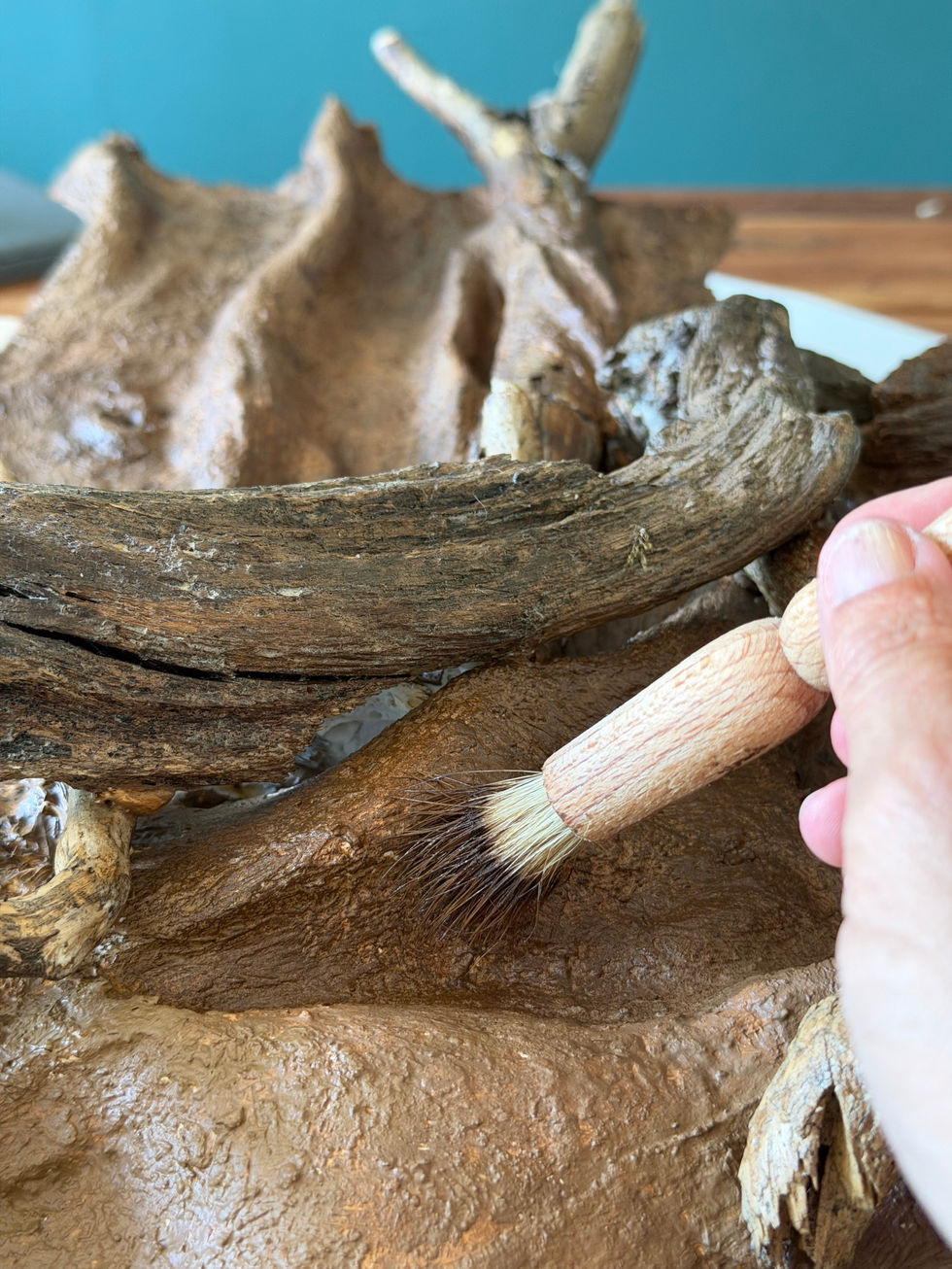 Hand brushing paint onto a sculptured piece in progress