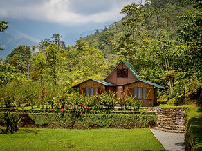 Covered wood and bamboo patio with dining table overlooking tropical gardens and sweeping Talamanca mountain views in the Chirripó Valley, Costa Rica.