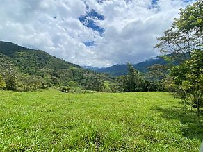 Panoramic mountain view from a property in the Chirripó Valley, with rolling green hills and sun-drenched pastures overlooking San José de Rivas, Costa Rica.
