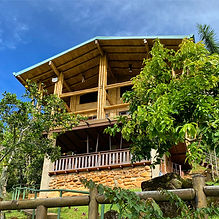 Three-story bamboo and stone home in the Chirripó Valley, Costa Rica, surrounded by fruit trees and tropical gardens with a wraparound balcony.
