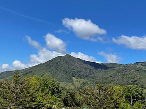 Panoramic mountain view from a property in the Chirripó Valley, with rolling green hills and sun-drenched pastures overlooking San José de Rivas, Costa Rica.