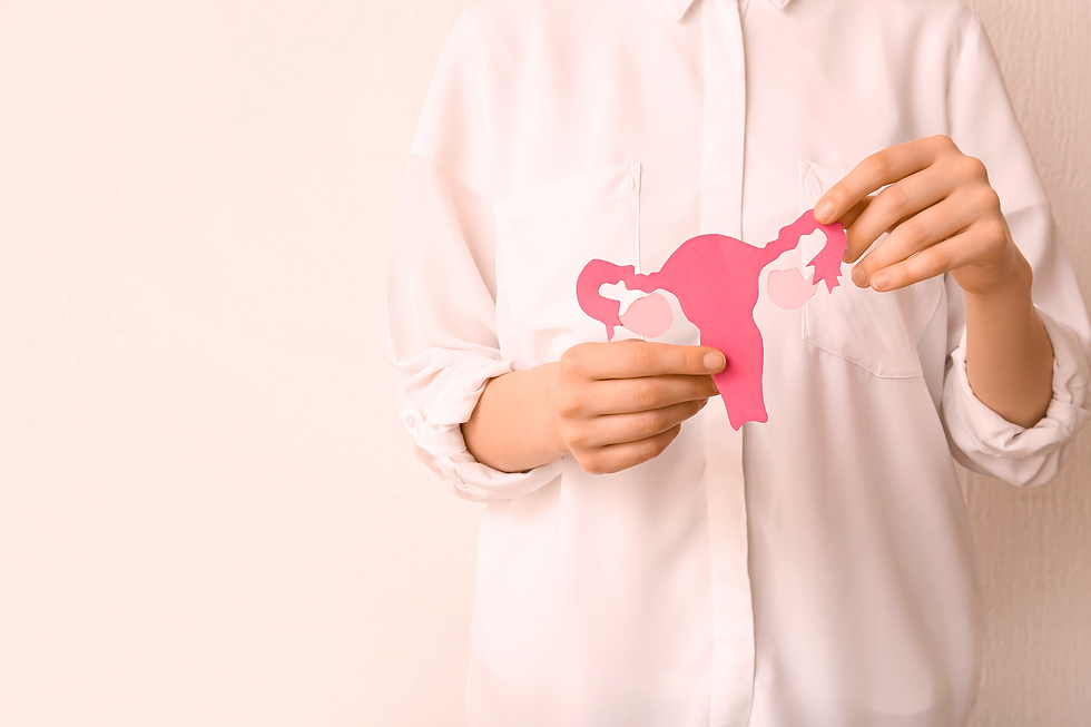 uma mulher de camisa branca, em um fundo rosa claro, segurando um útero de papel rosa escuro