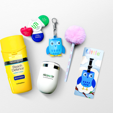 Custom branded promotional merchandise and gifts with purchase, including Neutrogena and Nicorette products, novelty keyrings, luggage tags and promotional accessories.